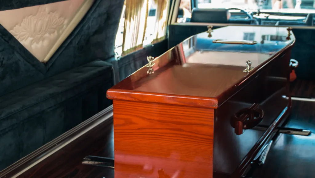 Cercueil en bois verni installé à l'intérieur d'un corbillard pour le transport funéraire